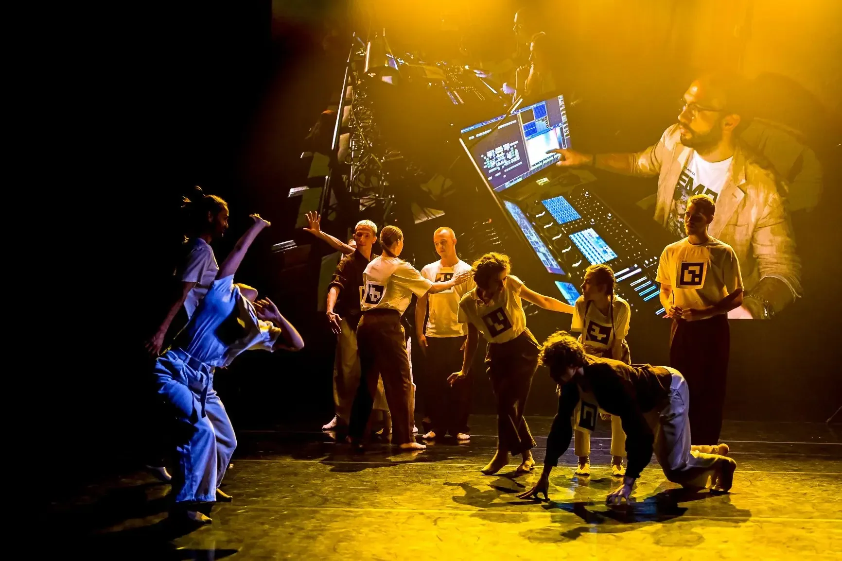 Performers and participants on stage in front of a technical projection.