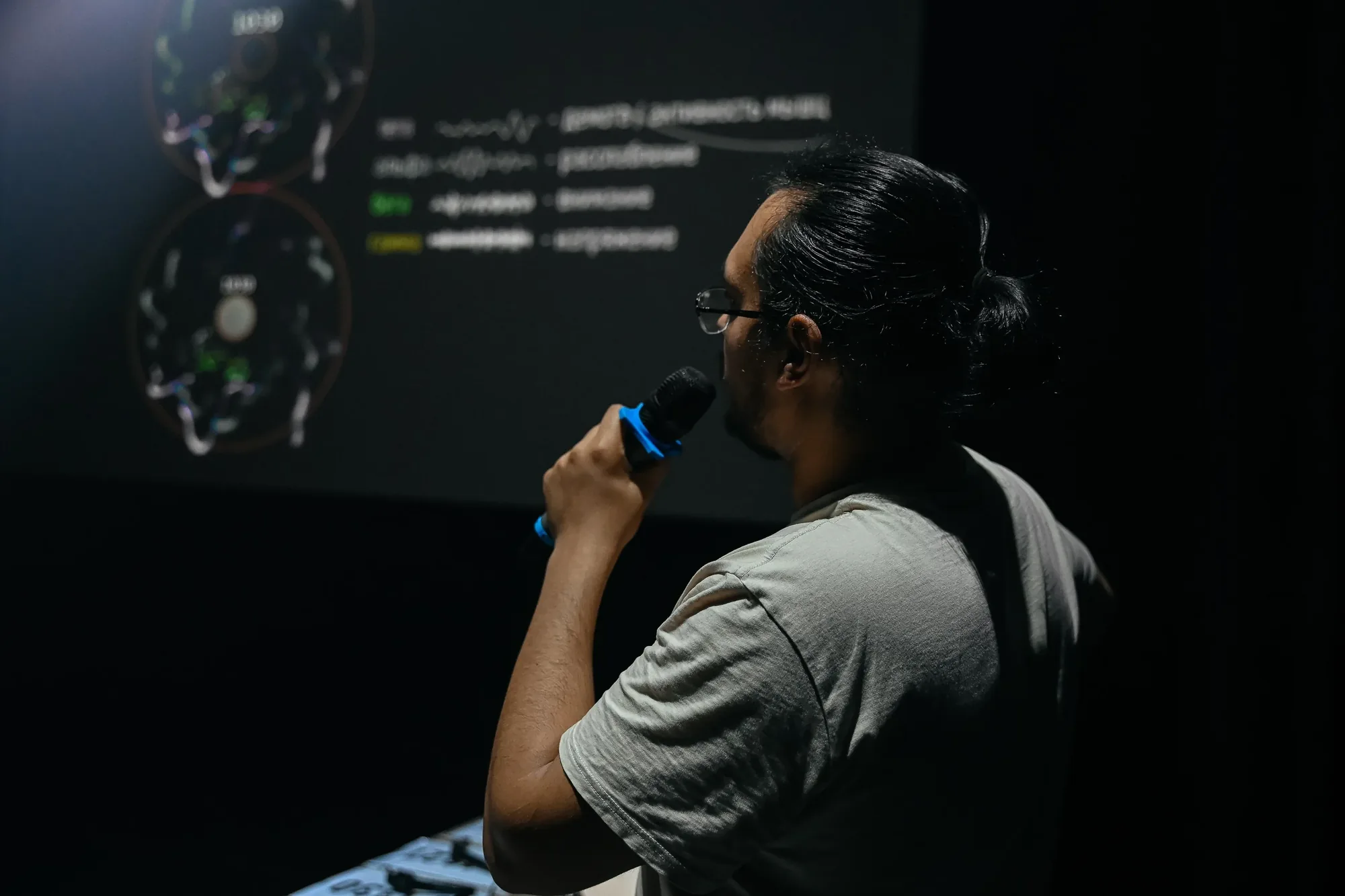 A facilitator holding a microphone in front of a technical projection.