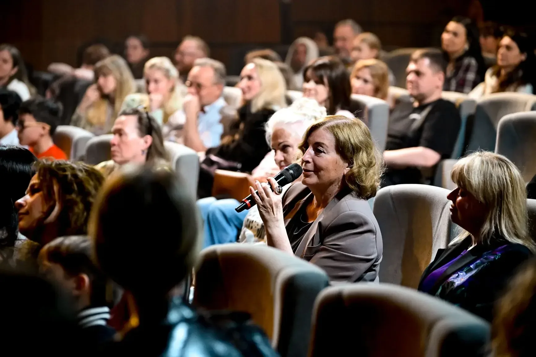 An audience member speaking into a microphone from her seat.