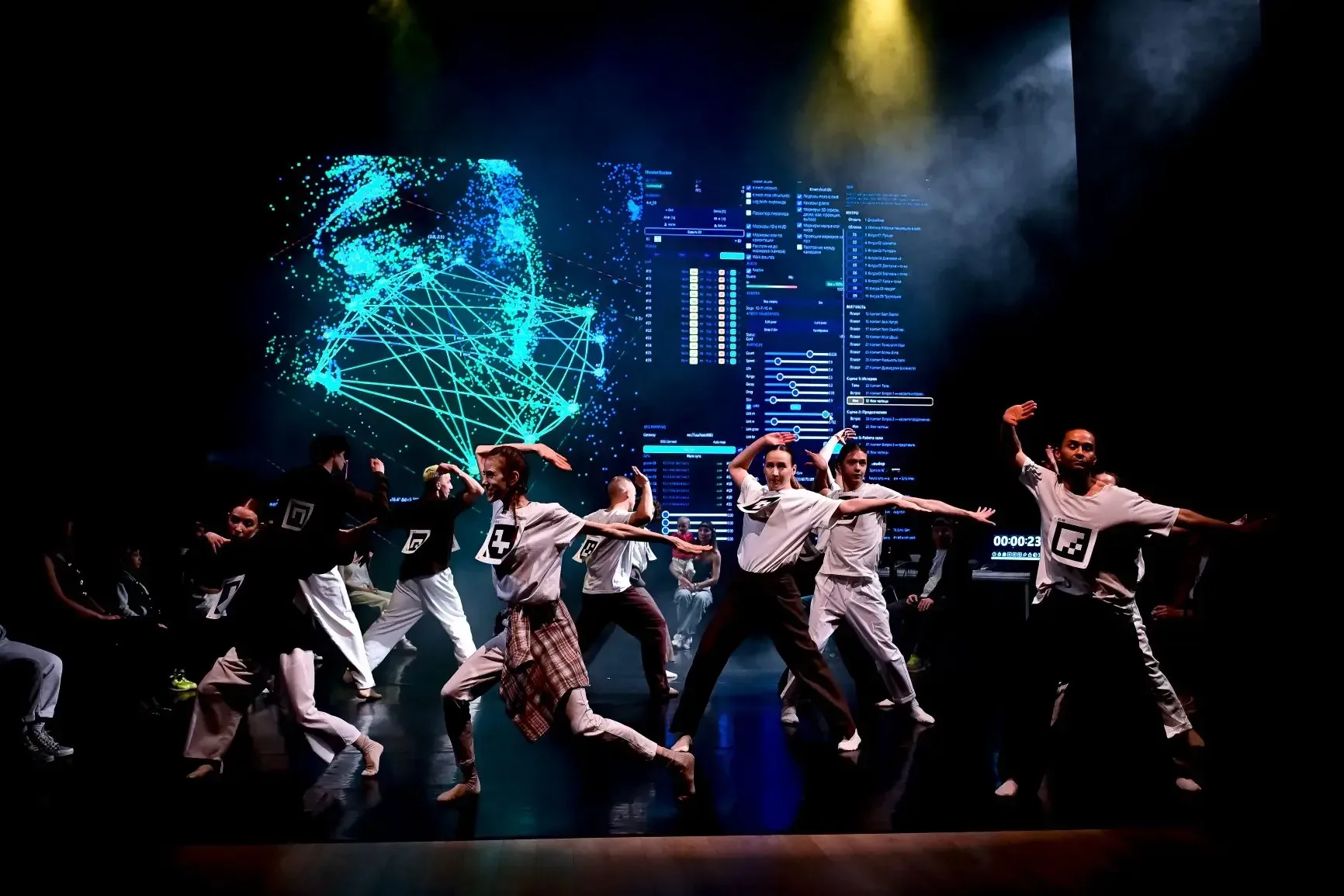 A group of dancers in front of a blue generative projection.