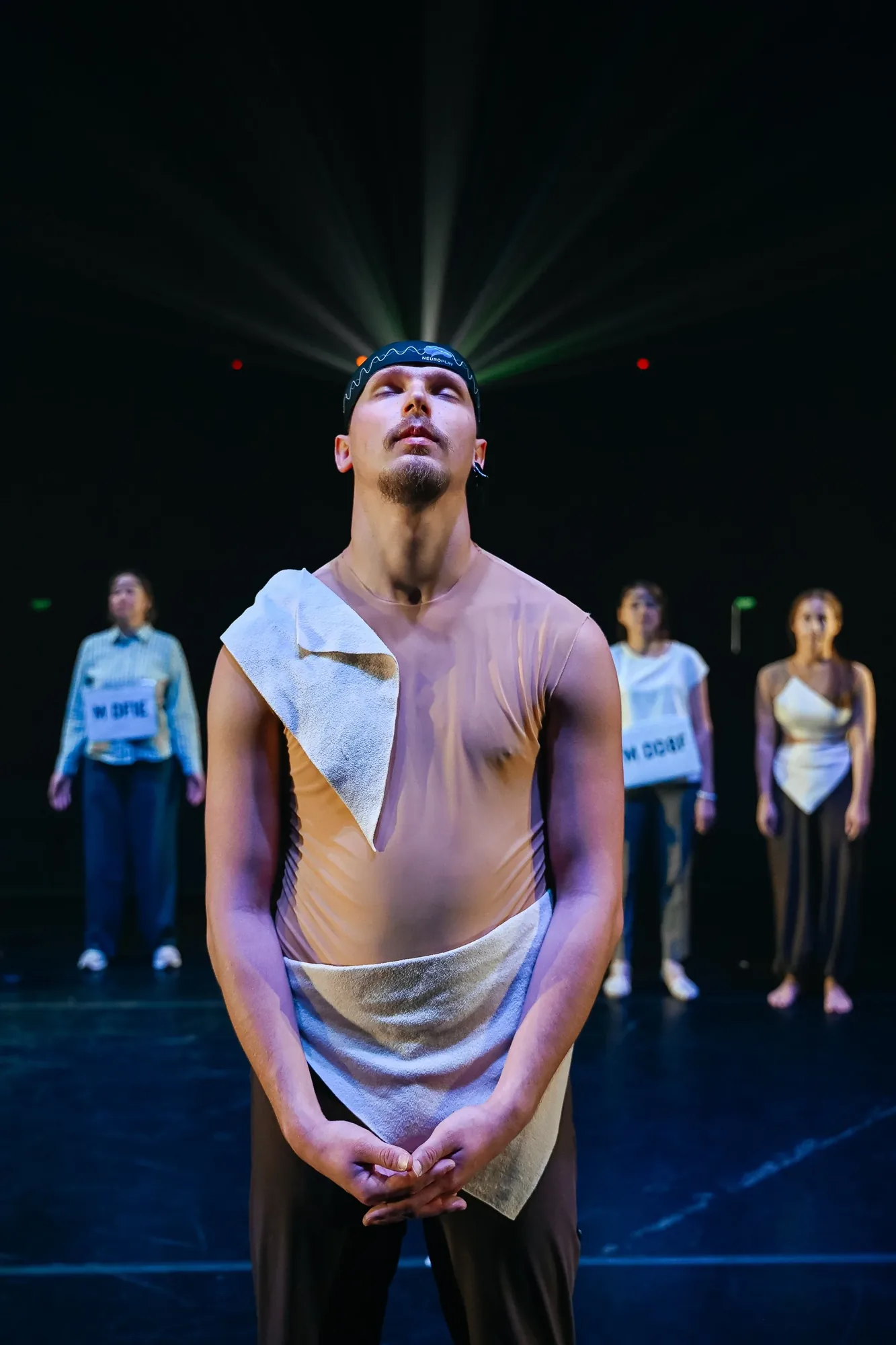 A performer wearing a neurointerface beneath spreading beams of light.
